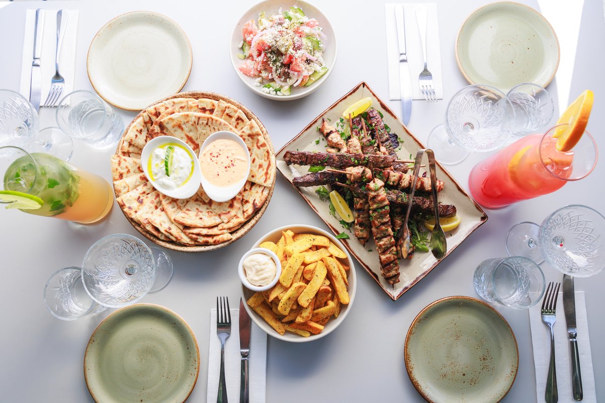 A full Greek table spread -dips, grilled meats, salad and pita
