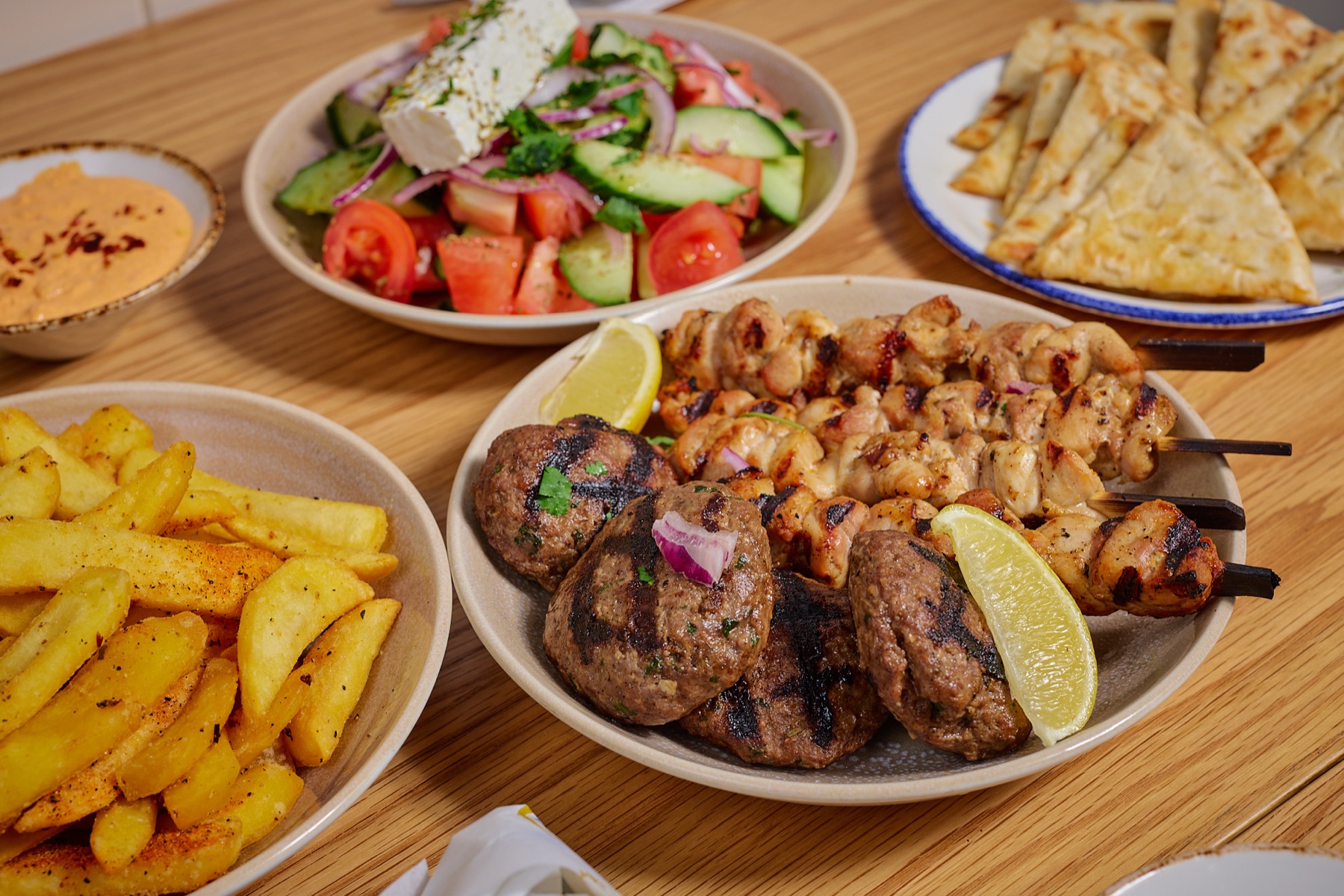 Yassas Greek shared table with chicken souvlaki, kofta, Greek salad, saganaki and chips